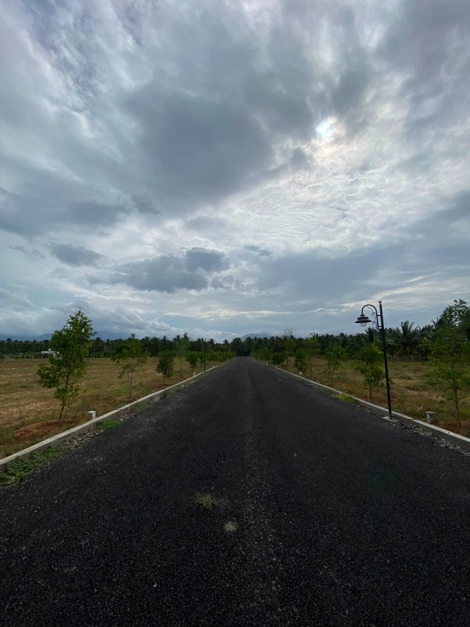 Internal road with vintage lamp posts under a monsoon sky